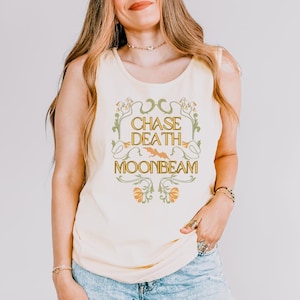 以下が含まれることがあります： 装飾的なフォントで「CHASE DEATH MOONBEAM」というテキストが入った、薄い黄色のタンクトップ。テキストは、緑とオレンジの花柄と葉のデザインで囲まれています。タンクトップはノースリーブです。