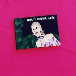 May include: A black and white illustration of a woman with blonde hair holding a martini glass. The text "Yeah, I'm drinking, Luann." is above her.