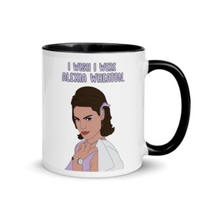 May include: White ceramic mug with a black rim and handle. The mug features a cartoon illustration of a woman with the text "I wish I were Alexia Wheaton."