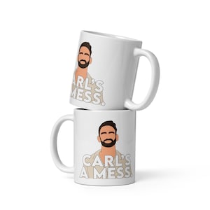 May include: Two white ceramic mugs stacked on top of each other. Each mug features a cartoon illustration of a man with a beard and the text "CARL'S A MESS." The mugs have a standard handle design.