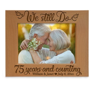May include: A wooden picture frame with the text "We still Do 75 years and counting William & Janet July 6, 20xx" engraved on it. The frame has a photo of an older couple embracing.