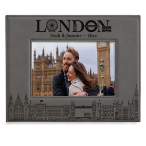 May include: A gray leather photo frame with a black and white photo of a couple in front of Big Ben in London. The frame has an engraved design of the London skyline and the text "LONDON UNDERGROUND Noah & Jasmine ~ 20xx".