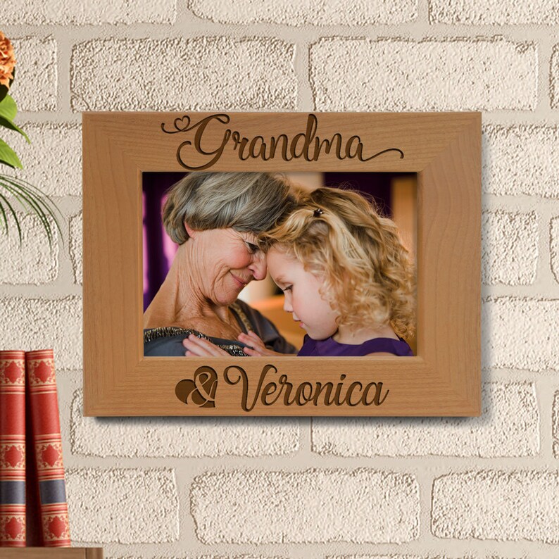 May include: A wooden picture frame with the words "Grandma & Veronica" engraved on it. The frame has a photo of an older woman and a young girl.