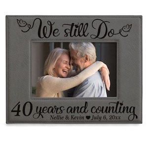 May include: Gray photo frame with a black inscription that reads "We still do 40 years and counting Nellie & Kevin July 6, 20xx". The frame has a picture of a couple smiling and hugging.