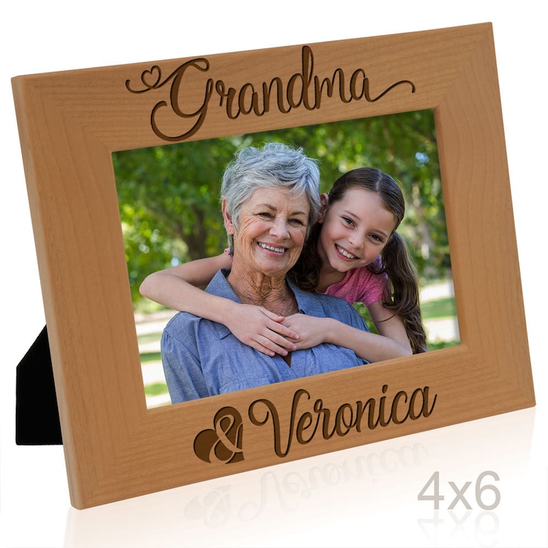 May include: A wooden picture frame with a 4x6 inch opening. The frame is engraved with the words "Grandma & Veronica" and a heart symbol.