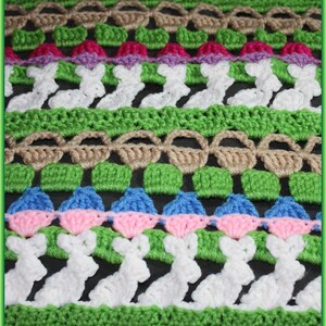 May include: A close-up of a crocheted blanket featuring a repeating pattern of baskets, squares, and bunnies. The blanket is made with green, brown, pink, blue, and white yarn.