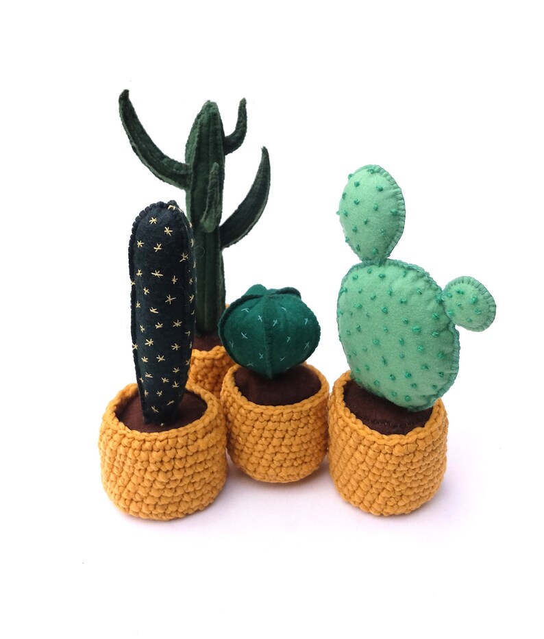May include: Four potted felt cactus plants in yellow crocheted pots. The cacti are green and have different shapes and textures.