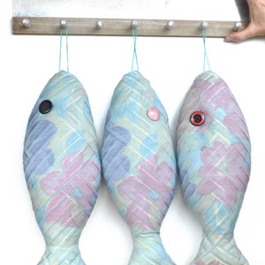 Peut inclure: Trois ornements en tissu en forme de poisson bleu et rose suspendus &agrave; un support en bois avec des crochets. Chaque poisson a un &oelig;il en bouton.