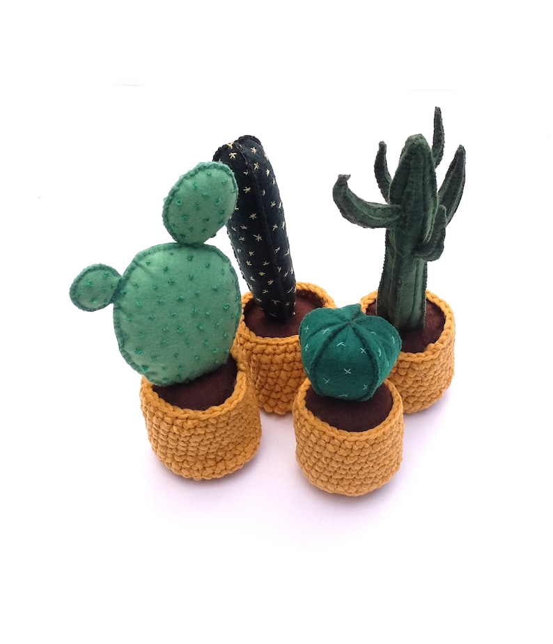 May include: Four felt cactus plants in yellow crocheted pots. The cacti are green and brown with different shapes and textures.