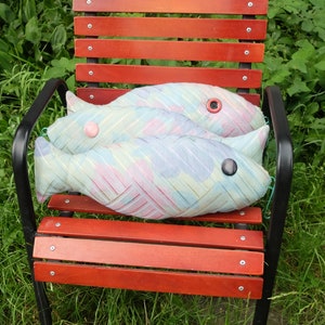 Peut inclure: Deux coussins en forme de poisson bleu et rose avec des yeux en boutons sur une chaise en bois rouge avec des pieds en m&eacute;tal noir.