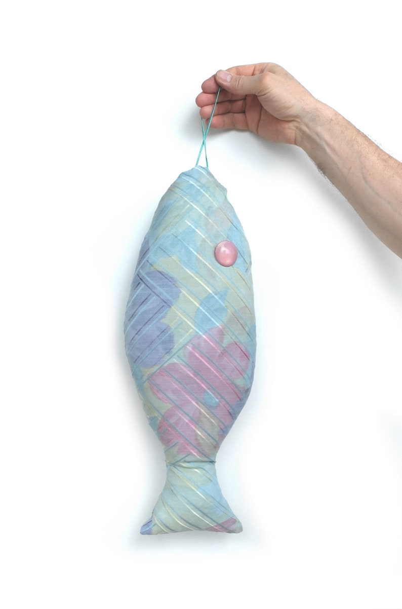 Peut inclure: Un poisson en tissu bleu et rose avec un bouton rose sur le c&ocirc;t&eacute;. Le poisson est suspendu &agrave; un &eacute;lastique bleu clair.