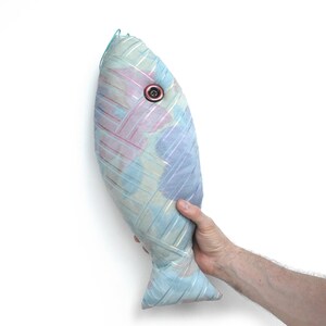 Peut inclure: Un coussin en forme de poisson bleu et rose avec un &oelig;il en bouton. Le coussin est fait d'un tissu doux et textur&eacute; et a un aspect l&eacute;g&egrave;rement d&eacute;lav&eacute;.