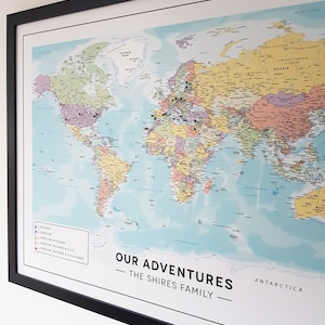 May include: A framed world map with colourful countries and a blue ocean. The map is decorated with push pins in various colours. The text "OUR ADVENTURES - THE SHIRES FAMILY -" is printed at the bottom of the map.
