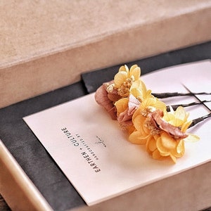 May include: Three yellow and brown dried flower hair clips in a small box with a pink card that says "Earthen Culture Handcrafted by"