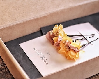 May include: Three yellow and brown dried flower hair clips in a small box with a pink card that says "Earthen Culture Handcrafted by"