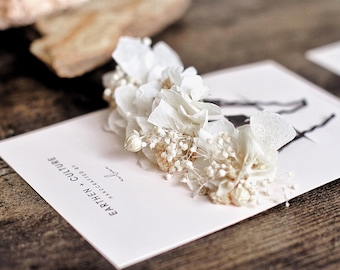 May include: White dried flower hair clip with a white card that says "EARTHEN + CULTURE HANDCRAFTED BY"