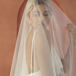 An image of model wearing drop veil with round petals for modern brides.