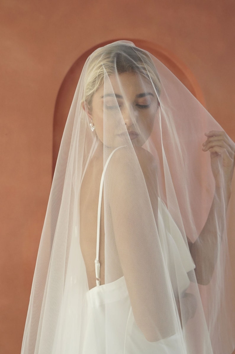 An image of model wearing drop veil with round petals for modern brides.