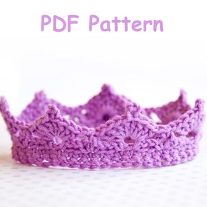 May include: A purple crocheted crown with a delicate, lacy design. The crown is made with a single crochet stitch and has a scalloped edge.
