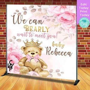 K&ouml;nnte beinhalten: Ein rosa-wei&szlig;er Babyparty-Hintergrund mit einem Teddyb&auml;r, der eine Krone und eine rosa Schleife tr&auml;gt. Der Text auf dem Hintergrund lautet "We can BEARLY wait to meet you! baby Rebecca".