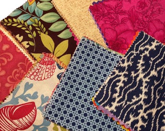 May include: A collection of fabric swatches with various patterns and colors. The swatches include floral, geometric, and textured designs in shades of red, pink, blue, green, and beige. Each swatch has a zig-zag edge.