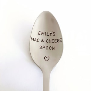 May include: A silver spoon with the text "Emily's Mac & Cheese Spoon" engraved on the front. A small heart is engraved below the text.