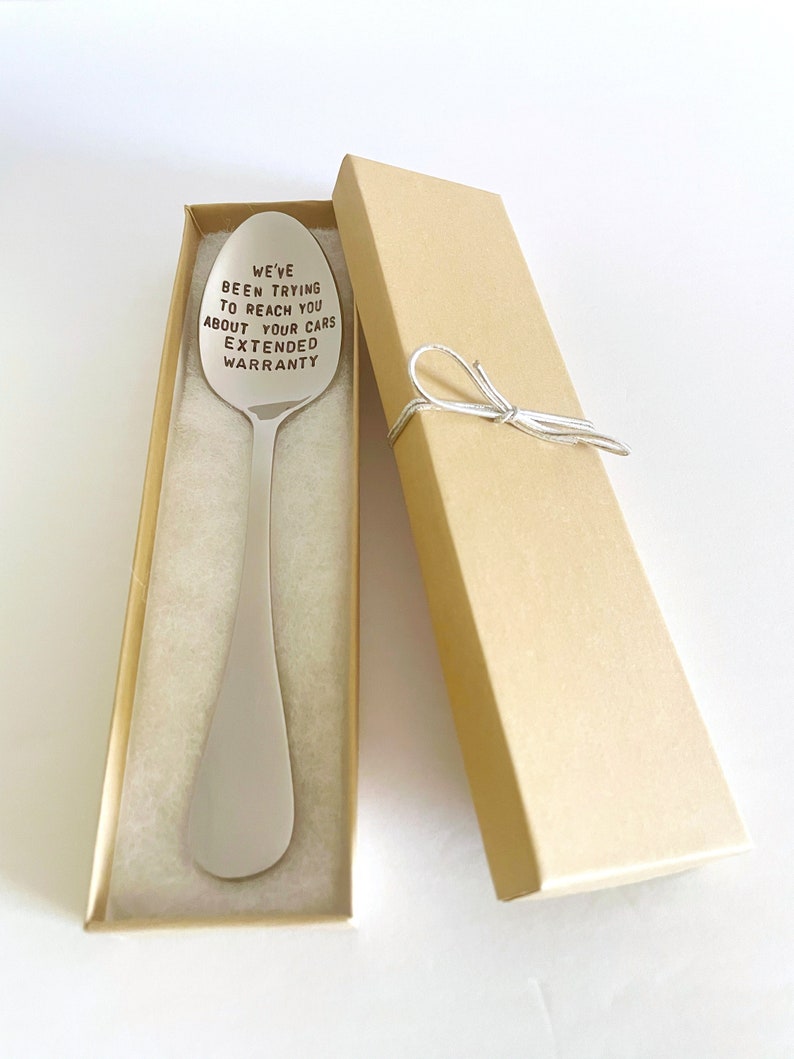 May include: A silver spoon with the text "We've been trying to reach you about your cars extended warranty" engraved on it. The spoon is in a brown gift box with a white ribbon.