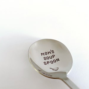 May include: A silver soup spoon with the words "Mom's Soup Spoon" engraved on the bowl. A small illustration of a bowl and spoon is also engraved on the spoon.