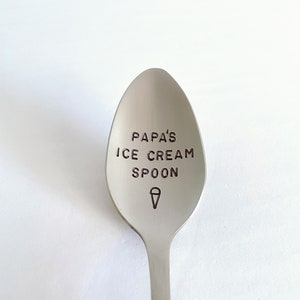 May include: A silver ice cream spoon with the text "Papa's Ice Cream Spoon" engraved on the bowl. An ice cream cone icon is also engraved on the bowl.