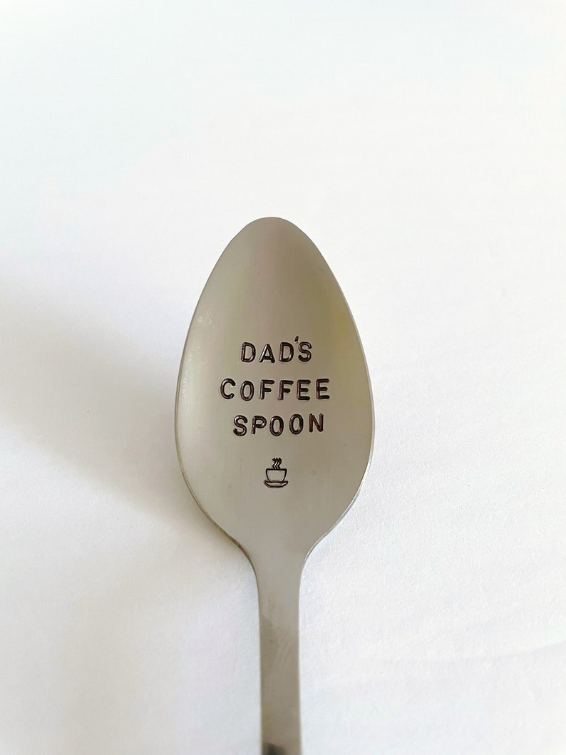 K&ouml;nnte beinhalten: Ein silberner L&ouml;ffel mit der Gravur "DAD'S COFFEE SPOON". Unter dem Text ist ein kleines Kaffeetassen-Symbol graviert.