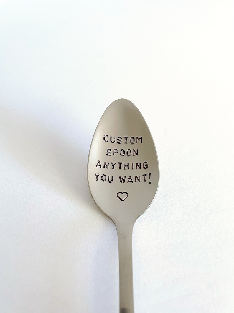 K&ouml;nnte beinhalten: Ein silberner L&ouml;ffel mit der Gravur "CUSTOM SPOON ANYTHING YOU WANT!" Ein kleines Herz ist unter dem Text graviert.