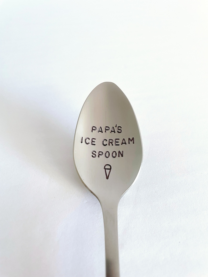 K&ouml;nnte beinhalten: Ein silberner Eis-L&ouml;ffel mit dem Text "Papa's Ice Cream Spoon" auf dem L&ouml;ffelkopf graviert. Ein Eiswaffel-Symbol ist ebenfalls auf dem L&ouml;ffelkopf graviert.