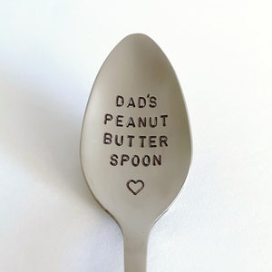 K&ouml;nnte beinhalten: Ein silberner L&ouml;ffel mit der Gravur "Dad's Peanut Butter Spoon". Unter dem Text ist ein kleines Herz graviert.