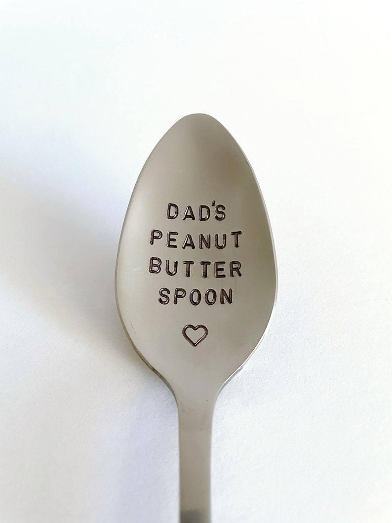 K&ouml;nnte beinhalten: Ein silberner L&ouml;ffel mit der Gravur "Dad's Peanut Butter Spoon". Unter dem Text ist ein kleines Herz graviert.