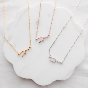 May include: Three delicate gold, rose gold, and silver necklaces with a constellation design. Each necklace features a small, detailed constellation pendant.