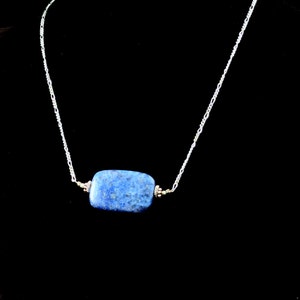 Op de afbeelding: Een zilveren ketting met een rechthoekige hanger van blauwe lapis lazuli.