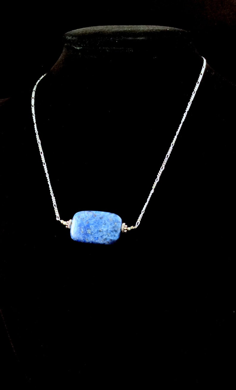 Op de afbeelding: Een zilveren ketting met een rechthoekige hanger van blauwe lapis lazuli.