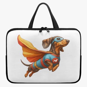 Op de afbeelding: Een witte laptoptas met een zwarte ritssluiting en handvatten. De tas heeft een kleurrijke illustratie van een teckel verkleed als superheld, compleet met cape en masker. De hond is bruin, bruin en blauw.