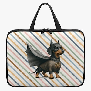 Op de afbeelding: Een zwarte laptoptas met een teckel verkleed als superheld, compleet met masker, cape en embleem. De achtergrond heeft een strepenpatroon in pastelkleuren. De tas heeft een zwarte ritssluiting en handvatten.