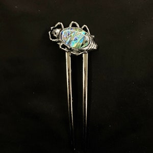 May include: Silver hair stick with a decorative iridescent abalone shell beetle design.