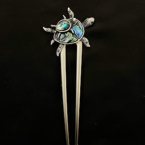 Puede incluir: Horquilla para el pelo de plata con un diseño decorativo de tortuga hecho de concha de abulón iridiscente.