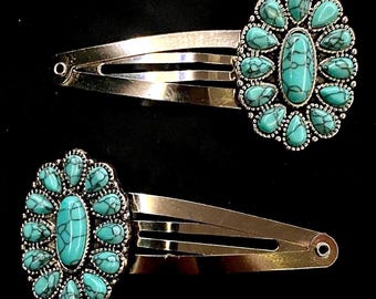 May include: Two silver-toned hair barrettes with turquoise-colored stone accents. Each barrette features an oval center stone surrounded by smaller teardrop-shaped stones. The barrettes are set against a black background.