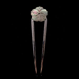 May include: A silver-toned hair pin with a carved flower design. The flower is a muted green with iridescent highlights. The pin has two long, parallel prongs.