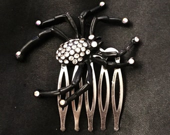 May include: Black spider hair comb with rhinestone accents. The spider has a jeweled body and black legs.