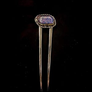 May include: A silver hair stick with a decorative, iridescent, blue and purple gemstone set in a silver bezel.