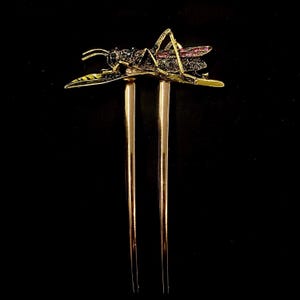 May include: Gold hair stick with a black and pink jeweled grasshopper design.