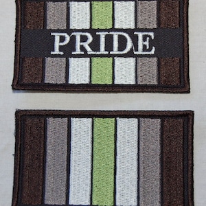 May include: Two embroidered patches with a pride flag design. The top patch has the word "PRIDE" in white text on a black background. Both patches feature a brown, gray, white, and green color scheme.