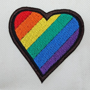 Peut inclure: Un patch en forme de cœur arc-en-ciel avec des rayures rouges, orange, jaunes, vertes, bleues, indigo et violettes.