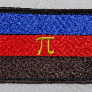 Könnte beinhalten: Ein blauer, roter und brauner gestickter Aufnäher mit einem gelben "π"-Symbol in der Mitte.