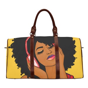 May include: A large, rectangular duffel bag featuring a vibrant illustration of a woman with dark skin, wearing headphones. The bag has brown leather handles and accents, with a yellow background and a black and red design.